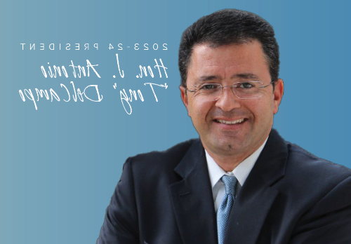 Smiling Latino man in a navy suit wearing glasses